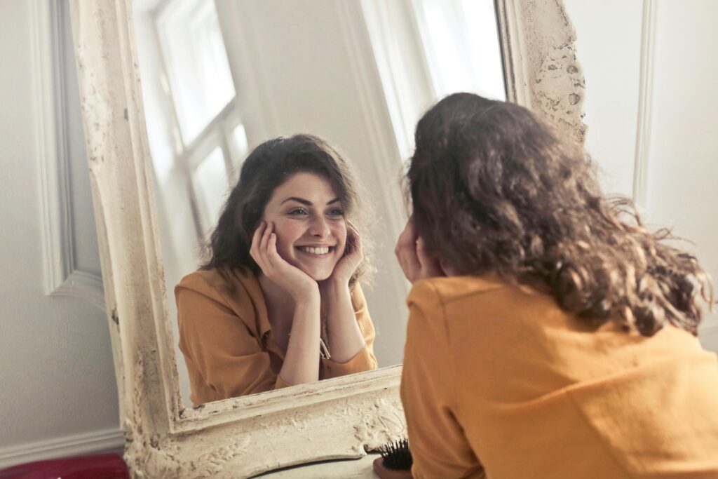 A cheerful mom smiles at her reflection—representing moms earning from home with a wellness-based side business.